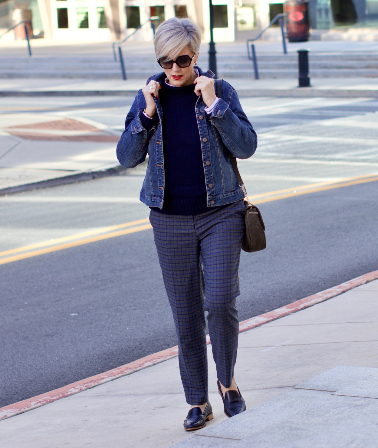 beth from style at a certain age wears a jean jacket, plaid pants, navy blue roll neck sweater, striped shirt, and navy blue loafers