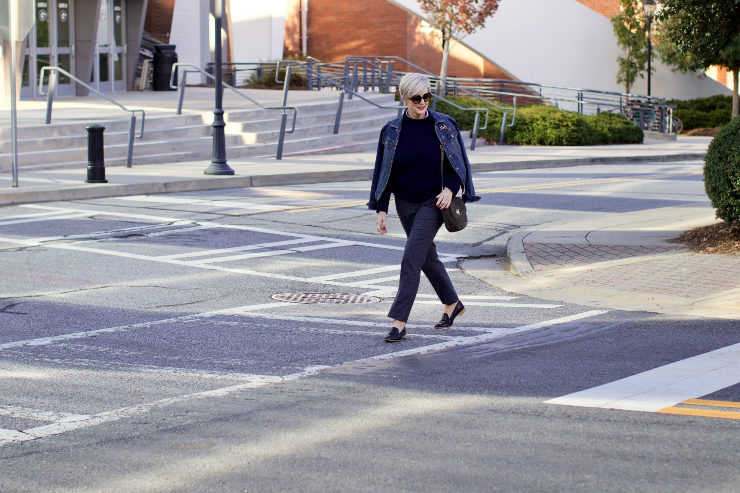 beth from style at a certain age wears a jean jacket, plaid pants, navy blue roll neck sweater, striped shirt, and navy blue loafers