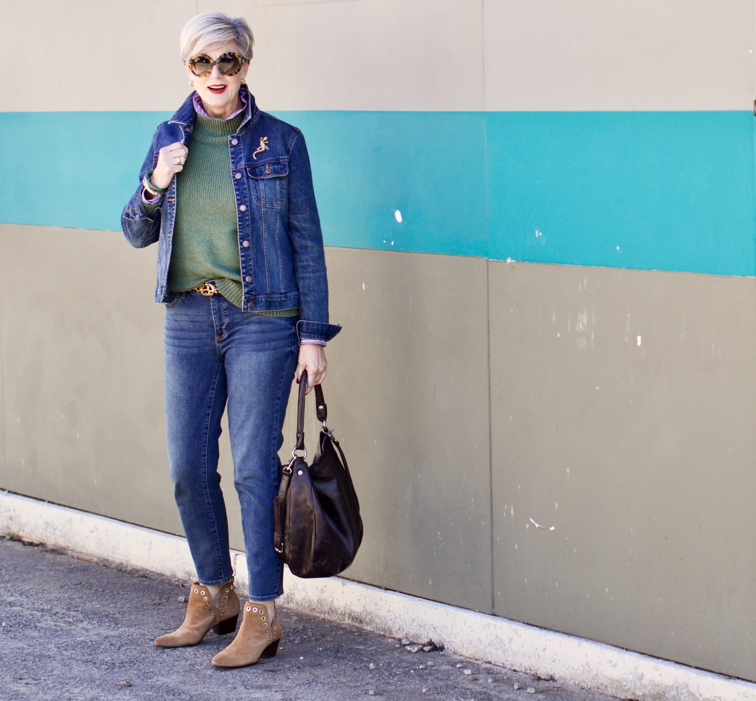 beth from Style at a Certain Age wears a chunky turtleneck layered over a stripe button down, skinny ankle jeans, a denim jacket, and booties