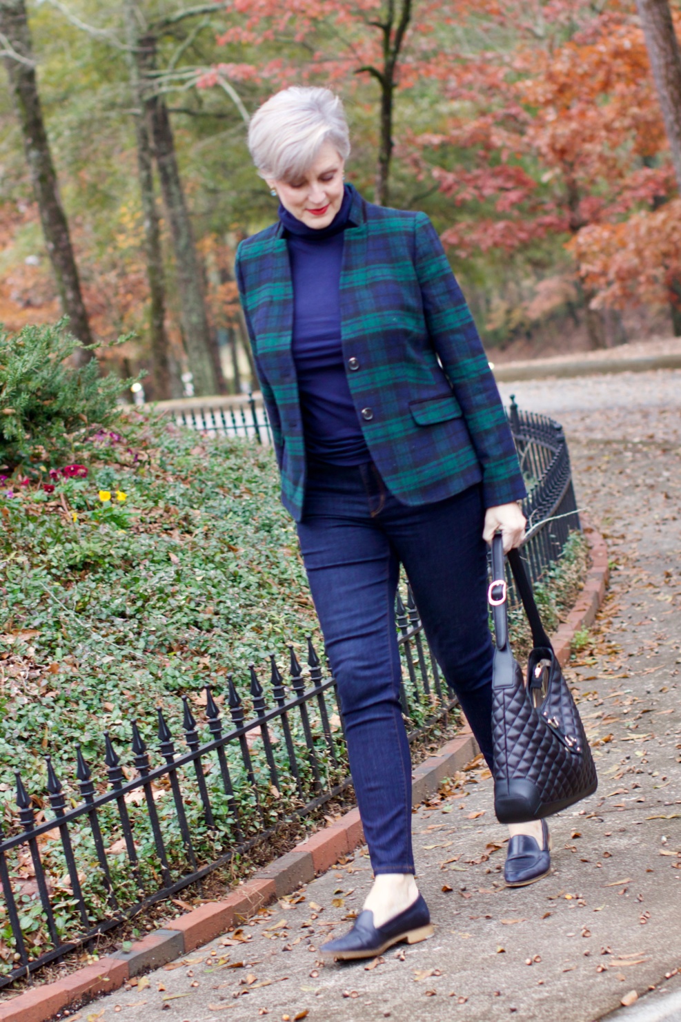 beth from Style at a Certain Age wears a black watch plaid blazer, tissue turtleneck, dark rinse denim, and navy blue loafers