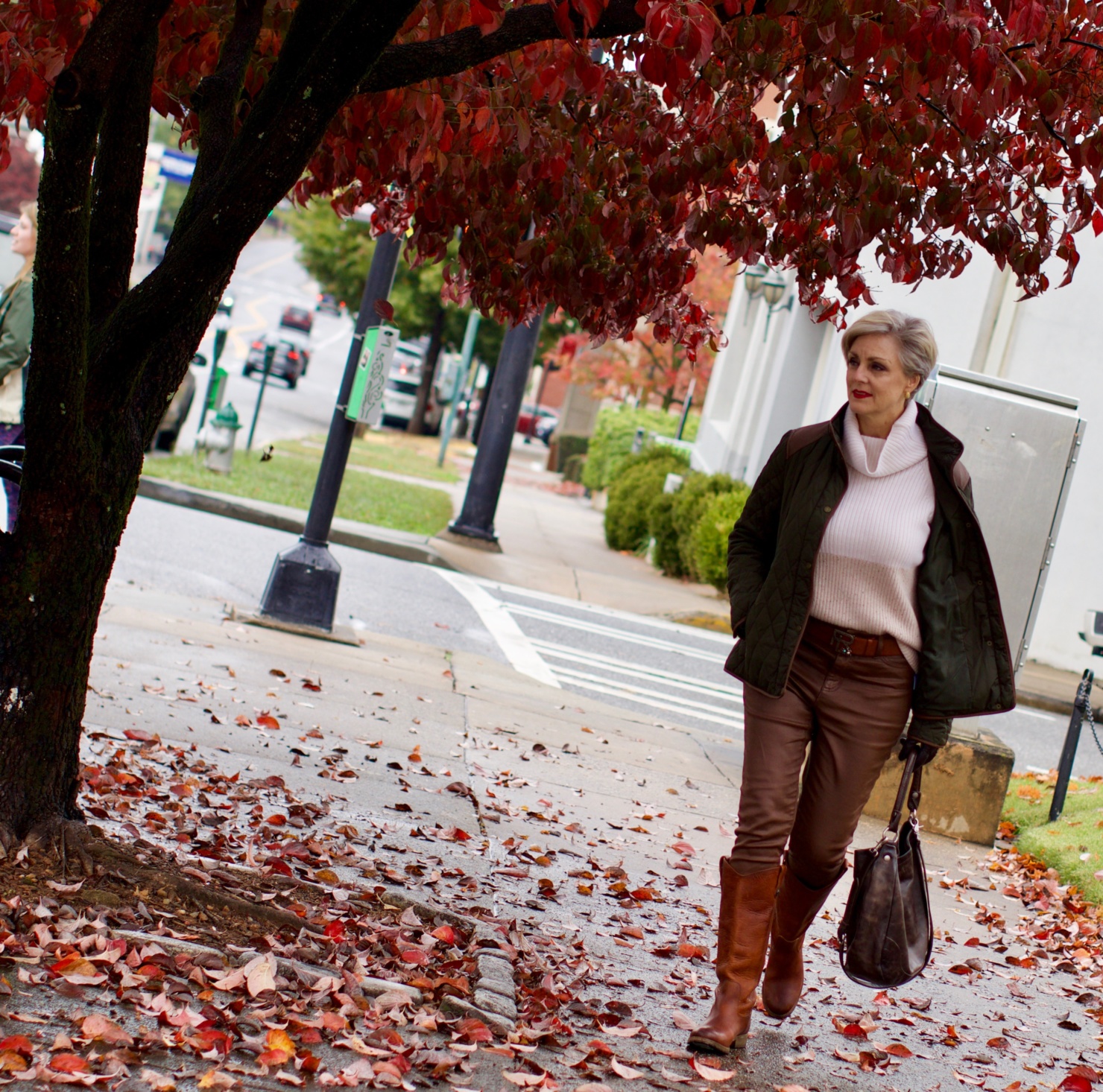 beth from Style at a Certain Age is wearing Ralph Lauren faux leather pants, chunky cashmere sweater, green utility jacket, Frye boots, and Frye hobo handbag
