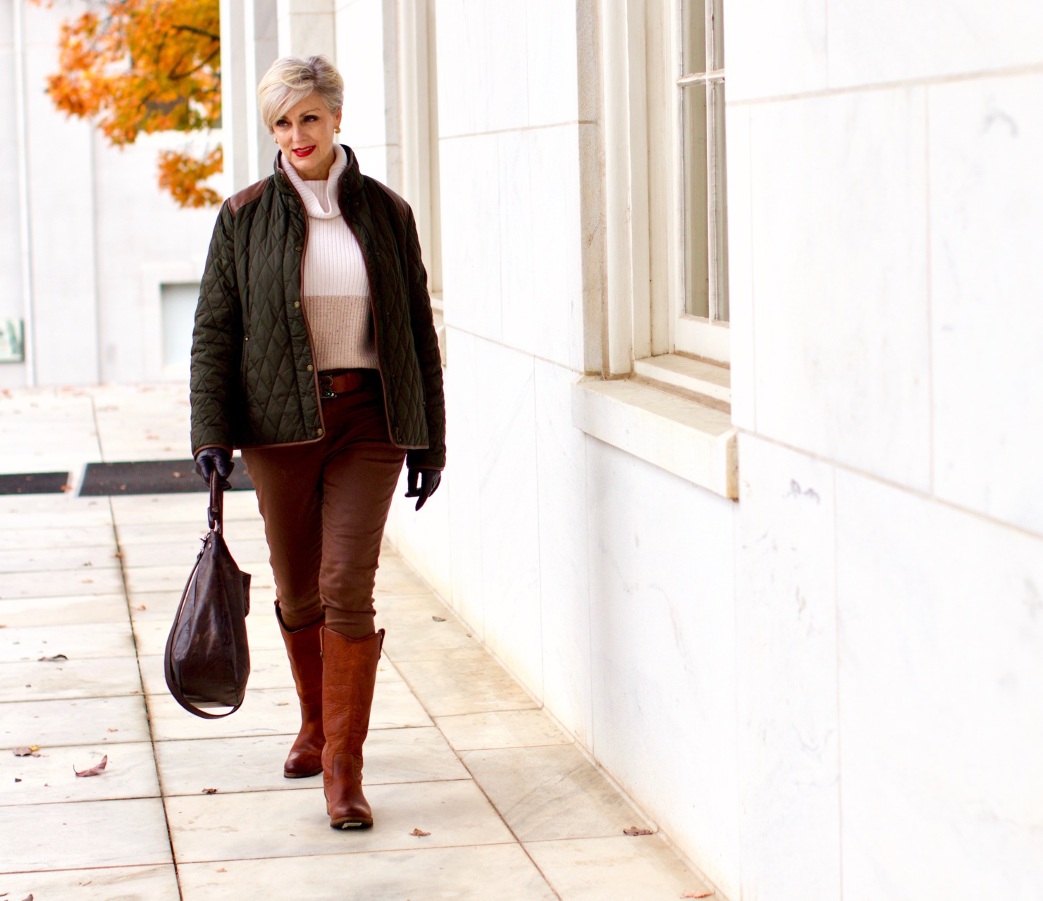 beth from Style at a Certain Age is wearing Ralph Lauren faux leather pants, chunky cashmere sweater, green utility jacket, Frye boots, and Frye hobo handbag