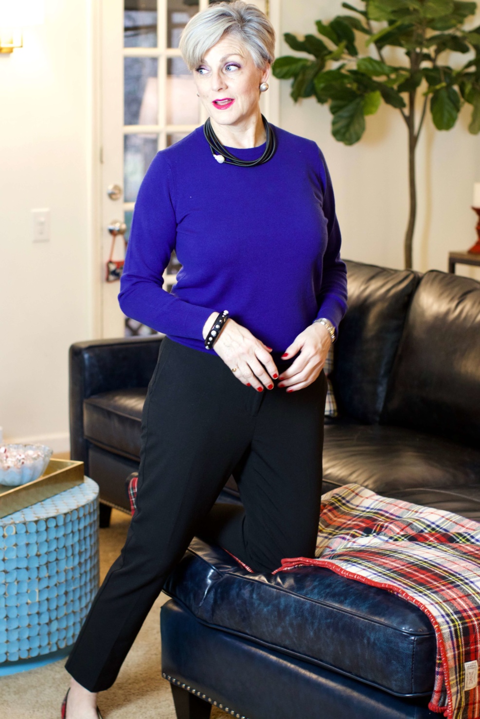 beth from Style at a Certain Age wears a cobalt blue cashmere crewneck, cropped black ankle pants, and tartan plaid flats