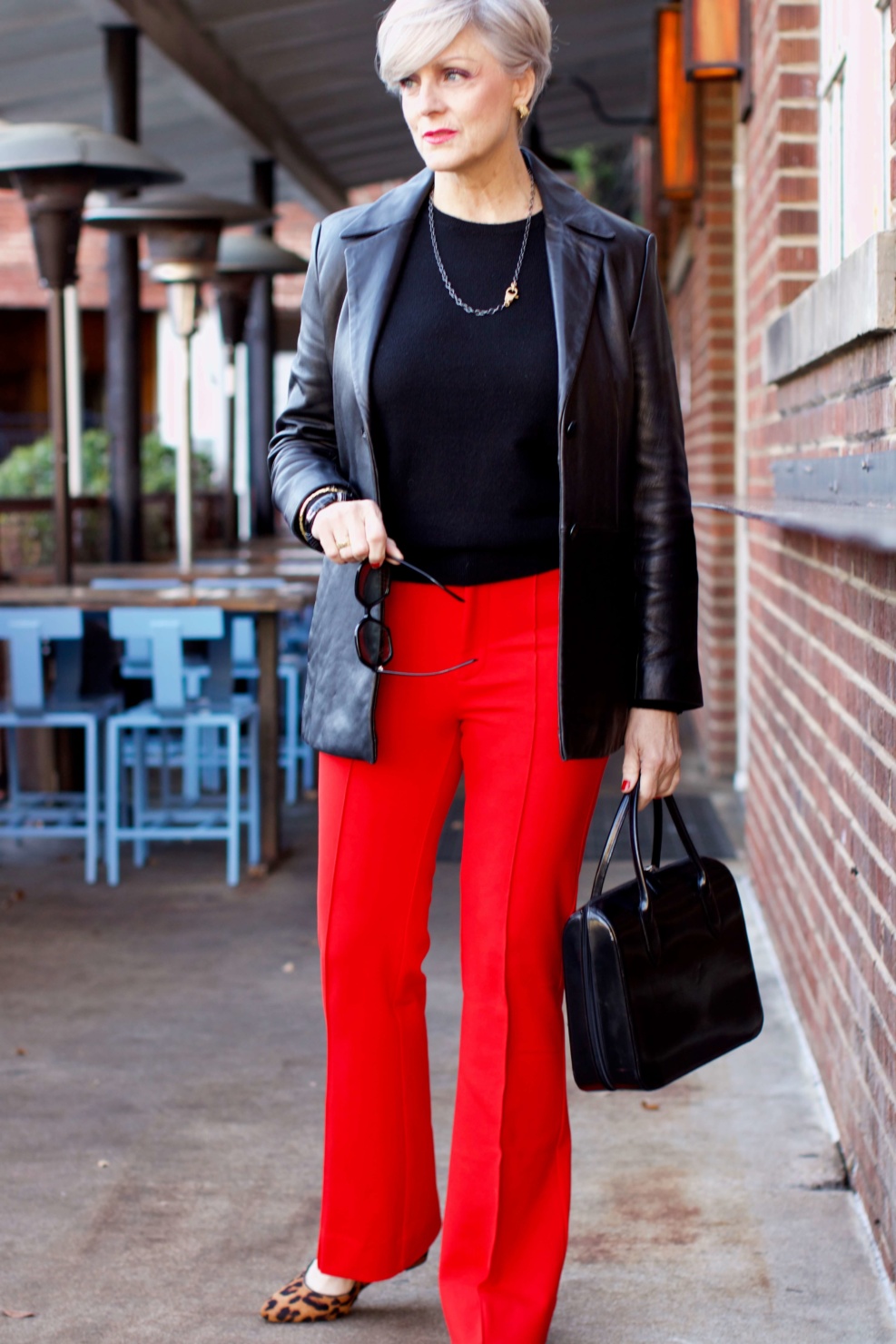 beth from Style at a Certain Age wears Anthropologie red pants, Everlane black cashmere crewneck, black leather blazer, and leopard pumps