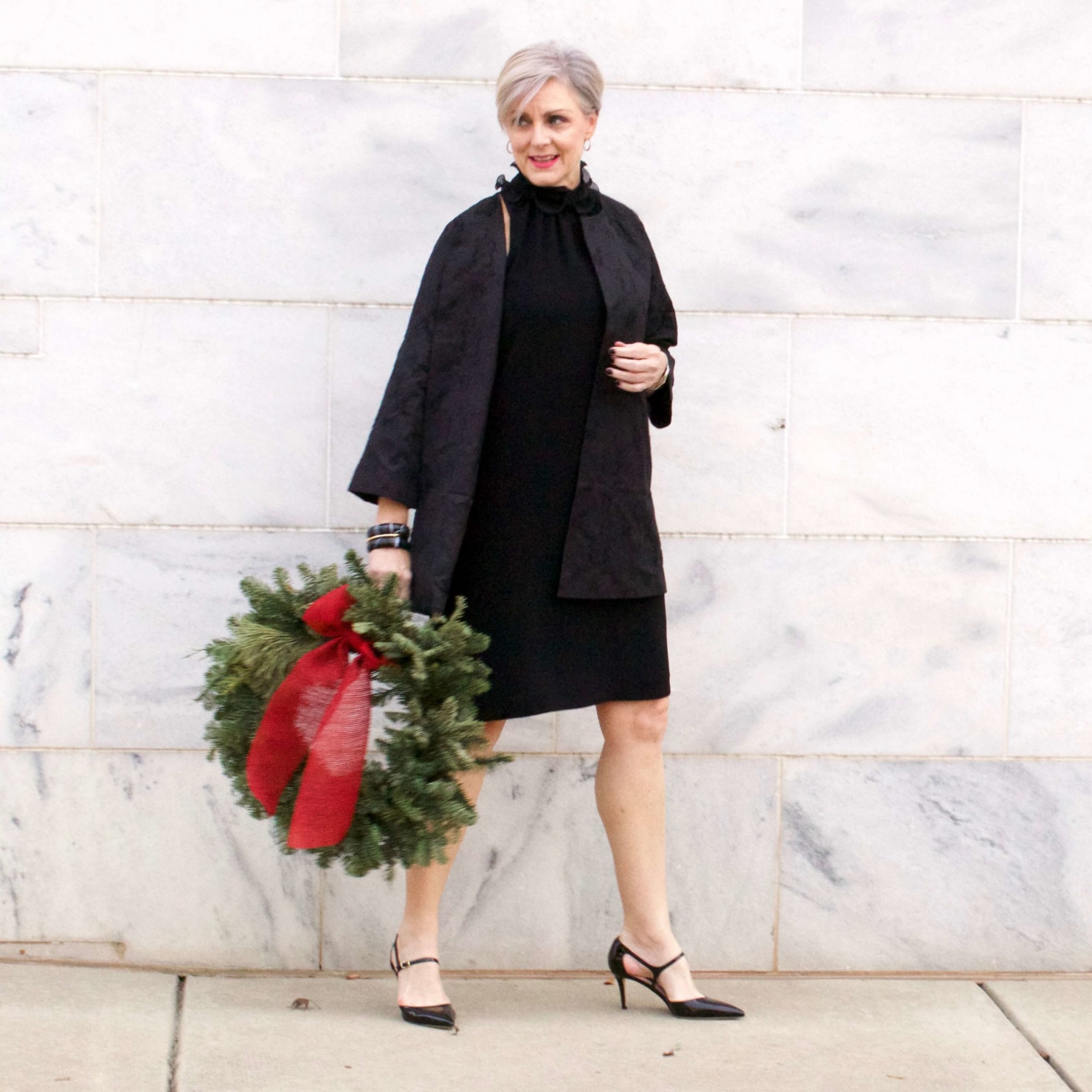 beth from Style at a Certain Age wears a Eileen Fisher shimmer jacquard 3/4 sleeve jacket and ruffled black dress