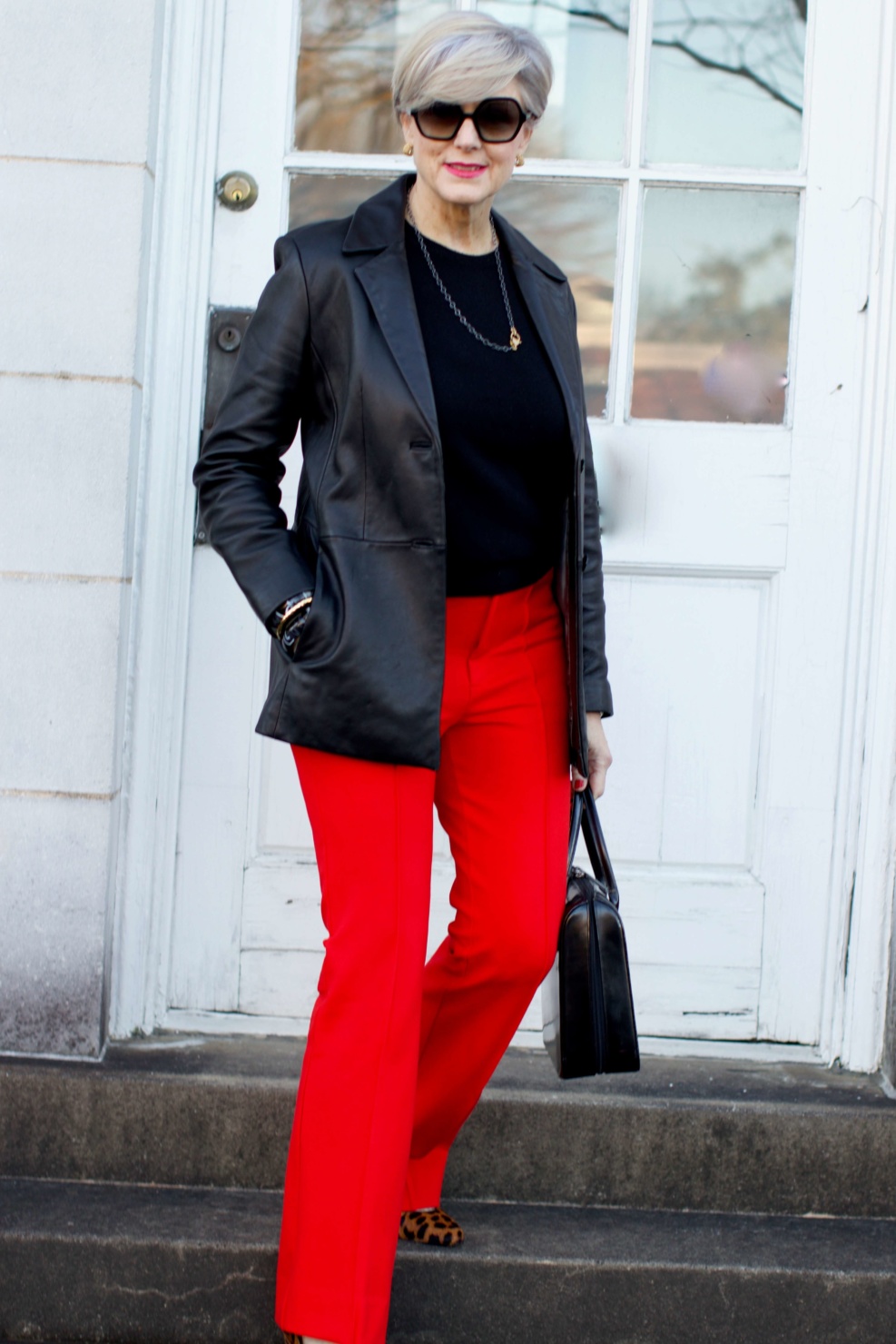 beth from Style at a Certain Age wears Anthropologie red pants, Everlane black cashmere crewneck, black leather blazer, and leopard pumps
