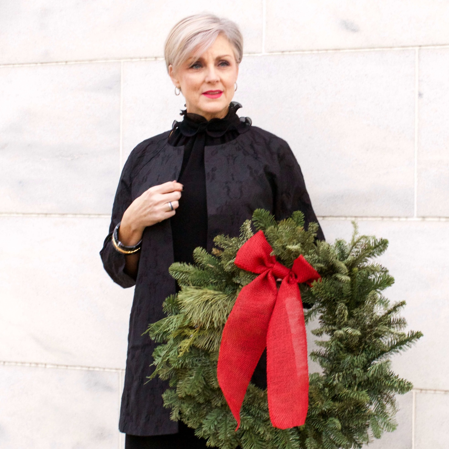 beth from Style at a Certain Age wears a Eileen Fisher shimmer jacquard 3/4 sleeve jacket and ruffled black dress 
