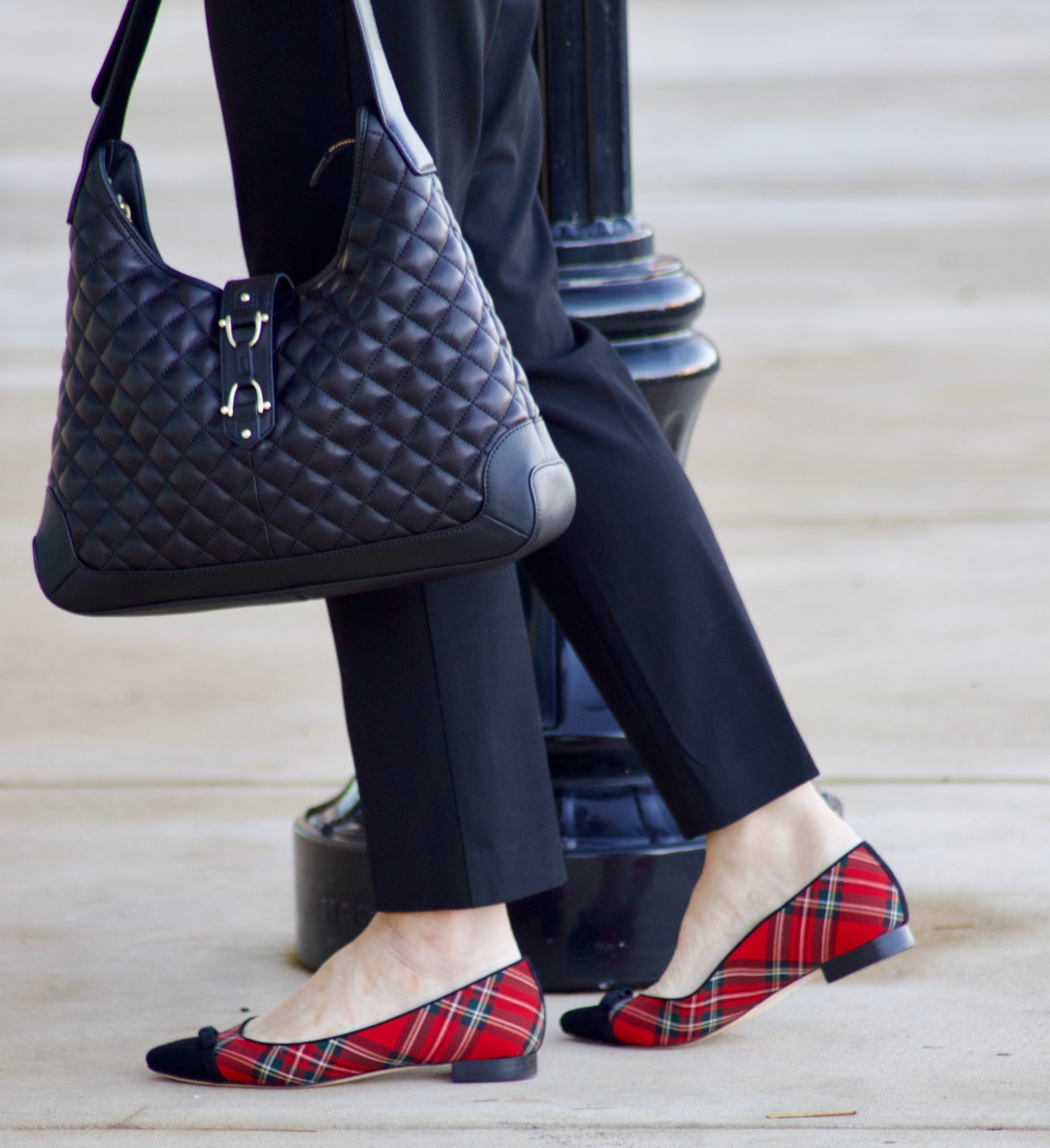beth from Style at a Certain Age wears a tartan plaid shirt, black cropped ankle pants, tartan plaid flats, military coat and quilted hobo handbag.