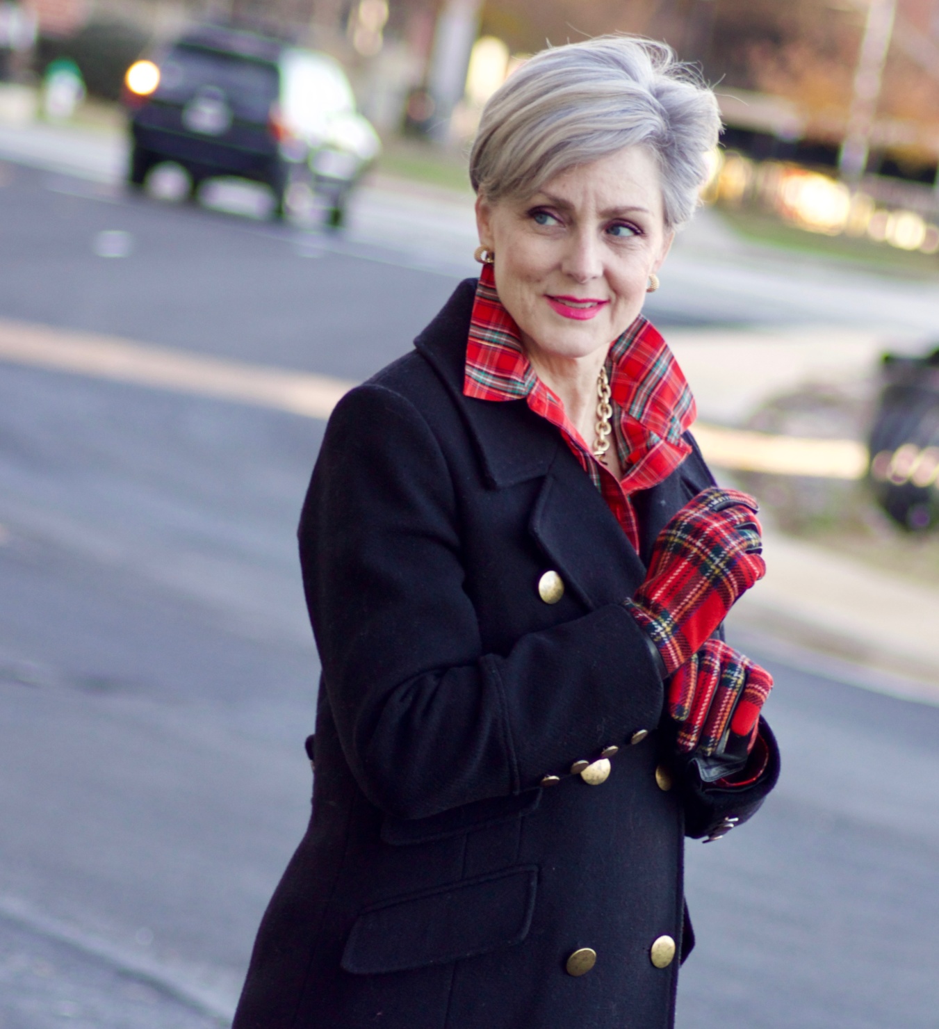 beth from Style at a Certain Age wears a tartan plaid shirt, black cropped ankle pants, tartan plaid flats, military coat and quilted hobo handbag.