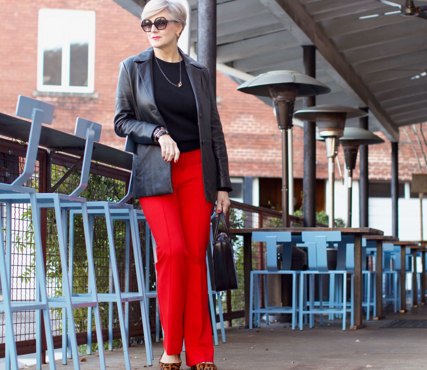 beth from Style at a Certain Age wears Anthropologie red pants, Everlane black cashmere crewneck, black leather blazer, and leopard pumps
