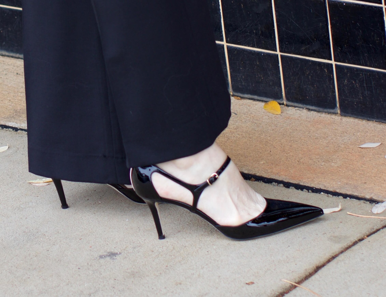 beth from Style at a Certain Age wears black flare pants, bow blouse, embroidered wonderland jacket, and black patent leather pumps