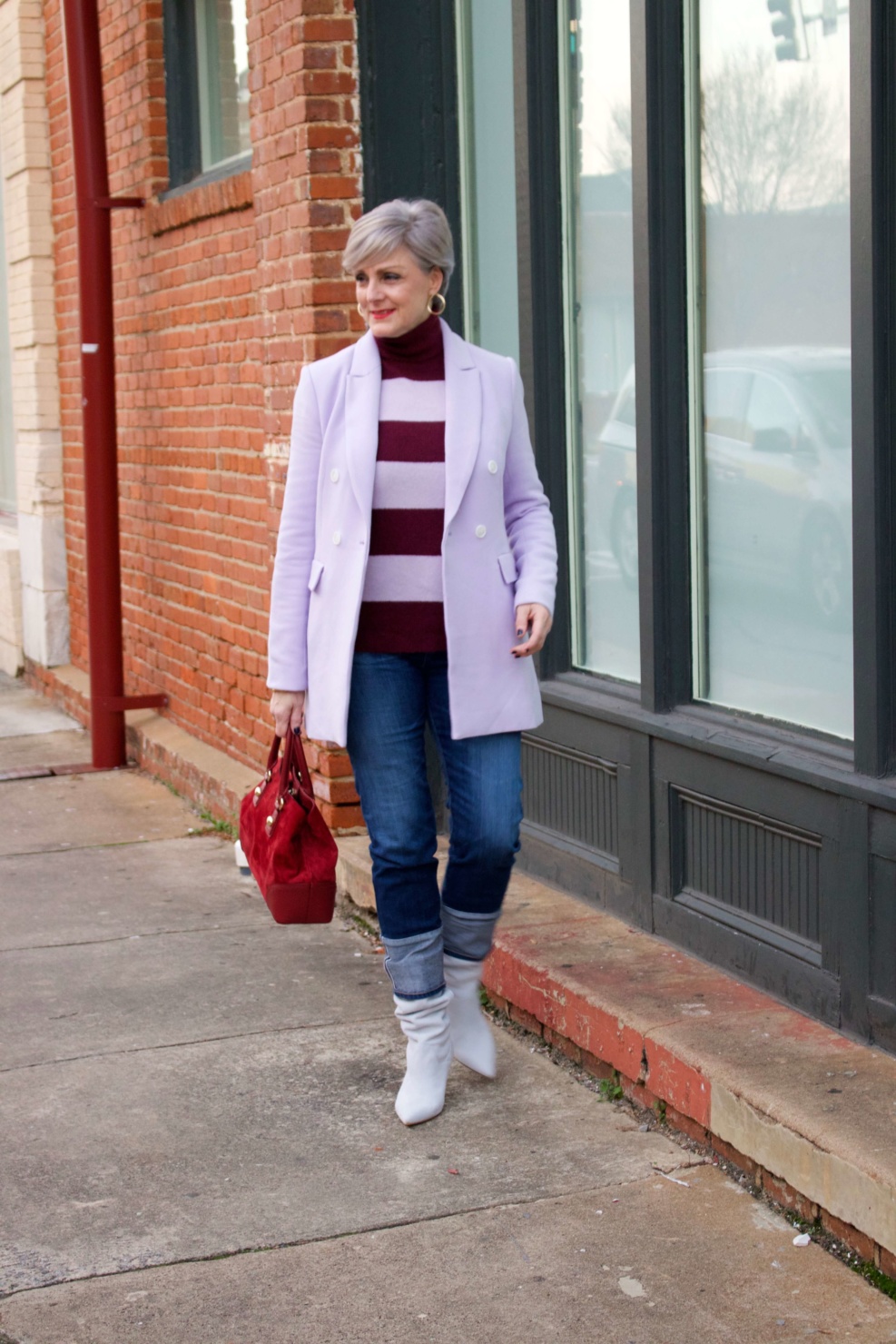 beth from Style at a Certain Age wears a striped turtleneck, lilac blazer, cuffed denim, grey suede boots