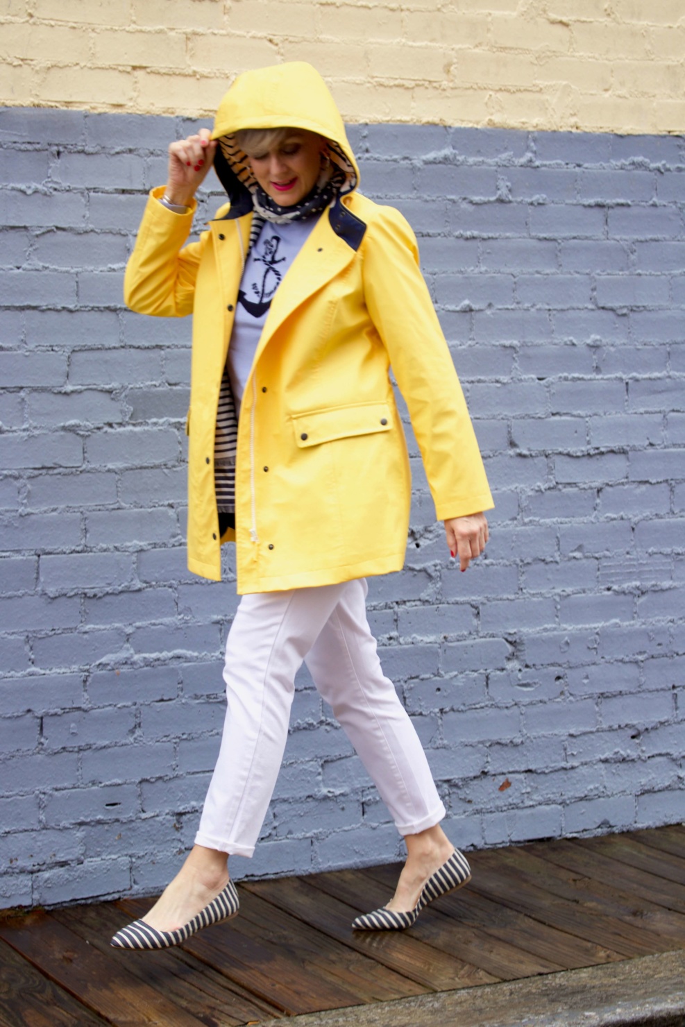 beth from Style at a Certain Age wears a yellow slicker from Talbots, white denim, anchor sweater, polka dot and striped scarf, and striped flats