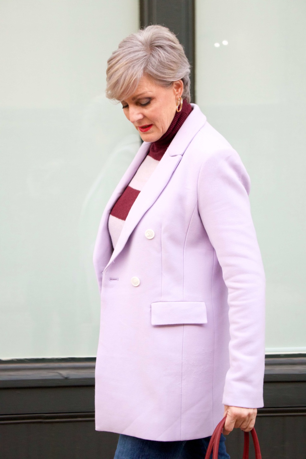 beth from Style at a Certain Age wears a striped turtleneck, lilac blazer, cuffed denim, grey suede boots