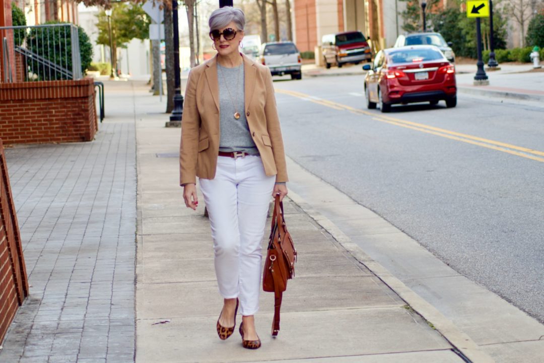 beth from Style at a Certain Age wears a camel blazer, grey cashmere crewneck, white denim, and leopard shoes