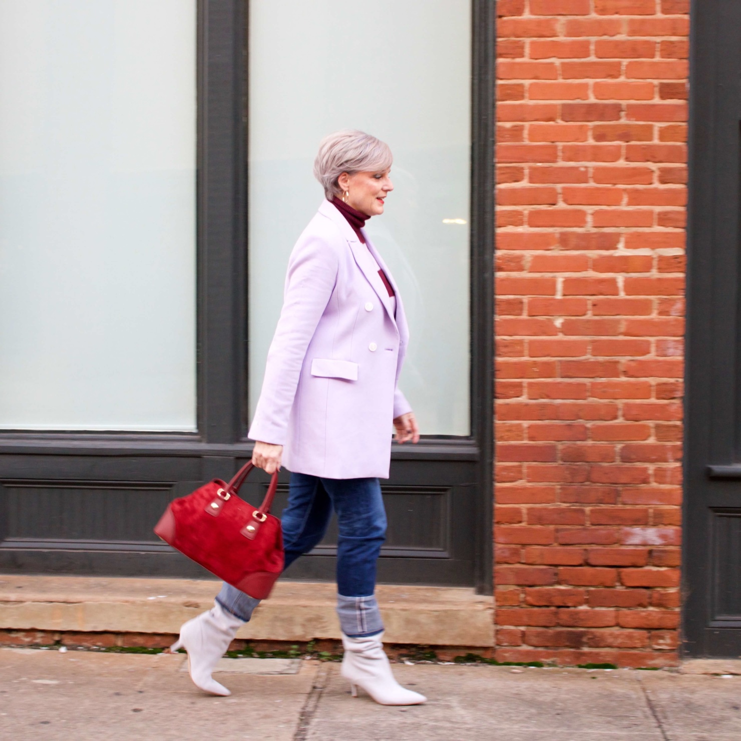 beth from Style at a Certain Age wears a striped turtleneck, lilac blazer, cuffed denim, grey suede boots