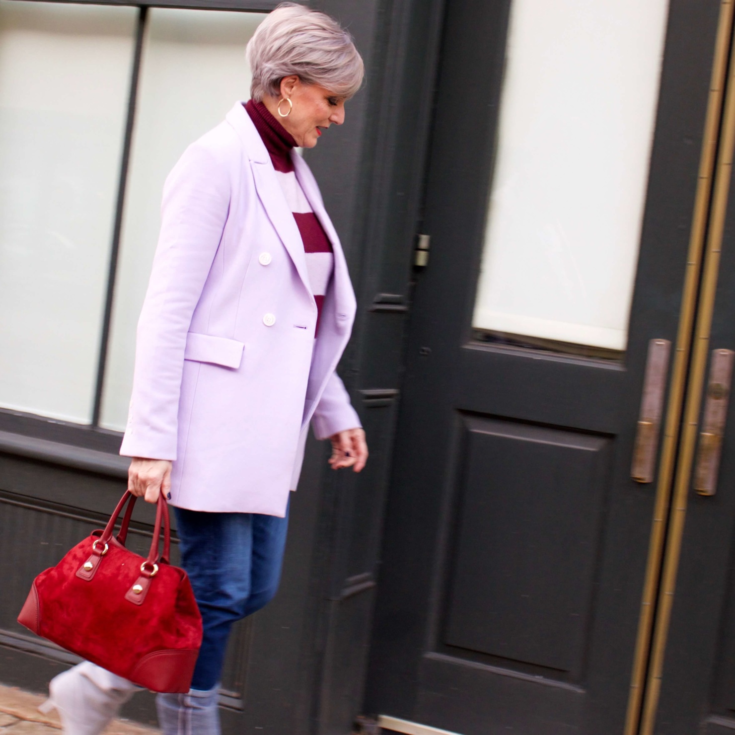beth from Style at a Certain Age wears a striped turtleneck, lilac blazer, cuffed denim, grey suede boots