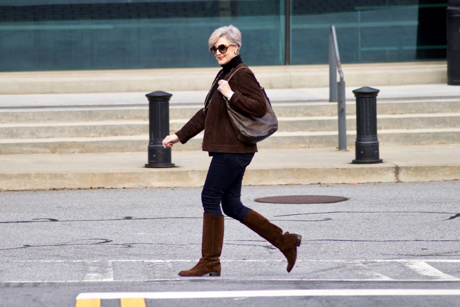 beth from Style at a Certain Age wears a black turtleneck, brown suede jacket, dark rinse denim and suede riding boots
