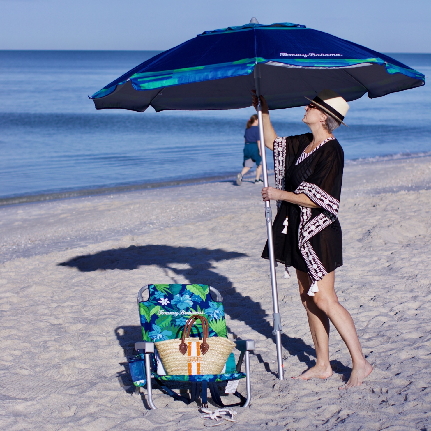 beth from Style at a Certain Age wears beach essentials, Ralph Lauren striped one-piece swimsuit, Tory Burch cover-up, jelly flip-flops, panama hat, and straw tote