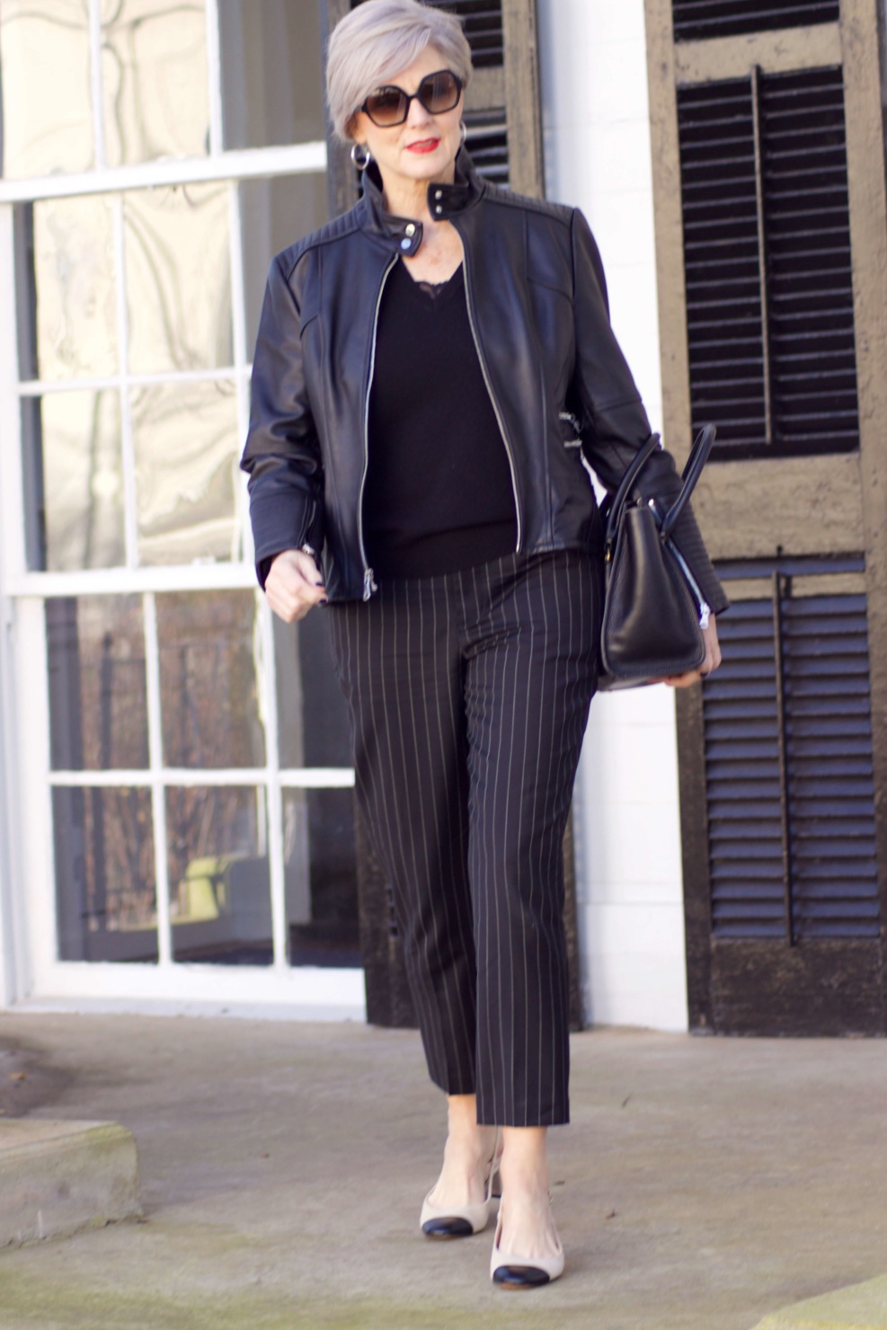 beth from Style at a Certain Age wears Ralph Lauren pinstripe pants, Everlane cashmere sweater, black leather moto jacket, and cap toe slingbacks
