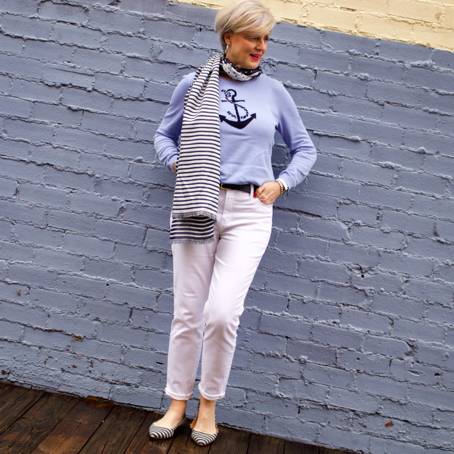 beth from Style at a Certain Age wears a yellow slicker from Talbots, white denim, anchor sweater, polka dot and striped scarf, and striped flats
