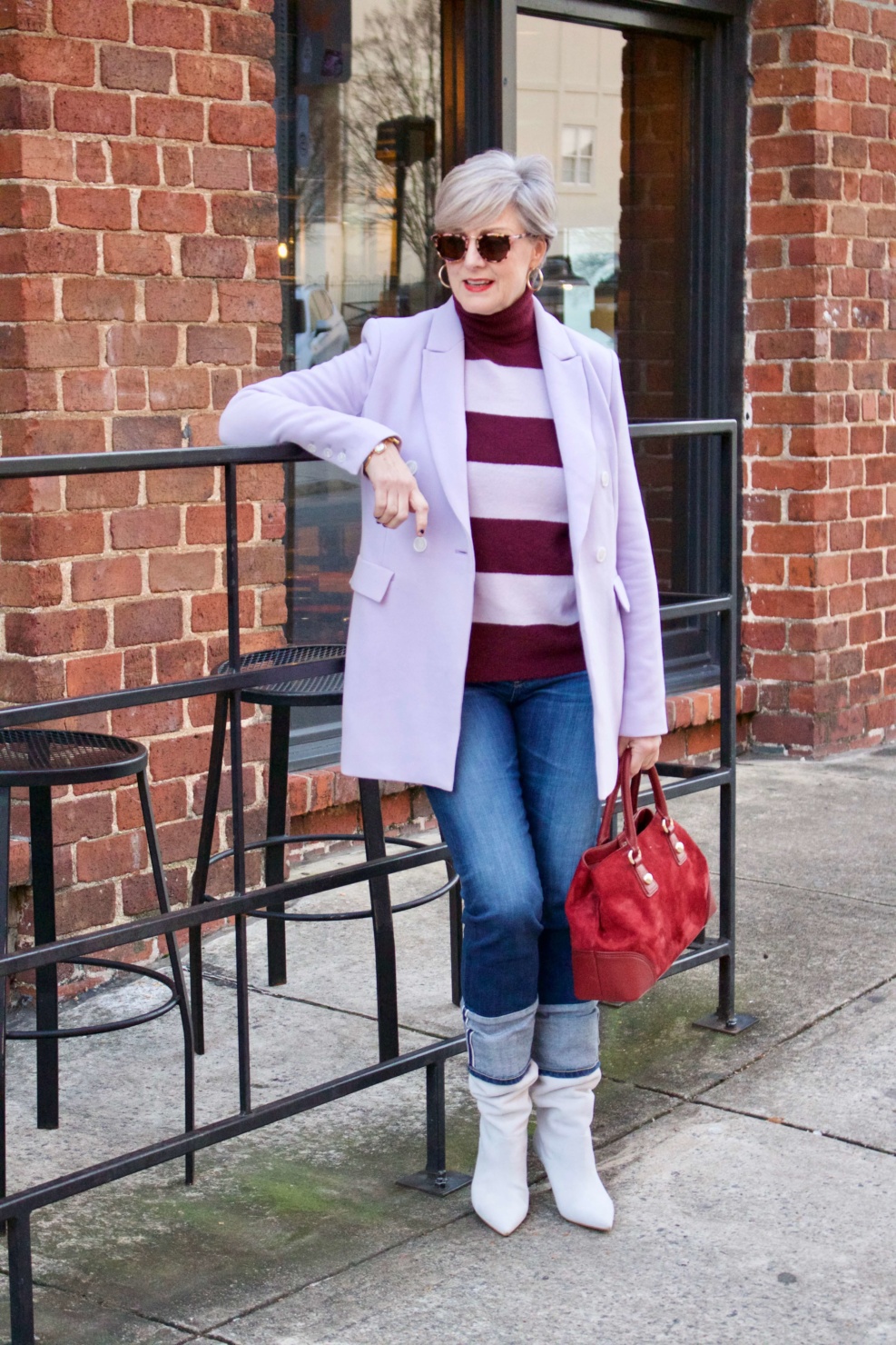 beth from Style at a Certain Age wears a striped turtleneck, lilac blazer, cuffed denim, grey suede boots