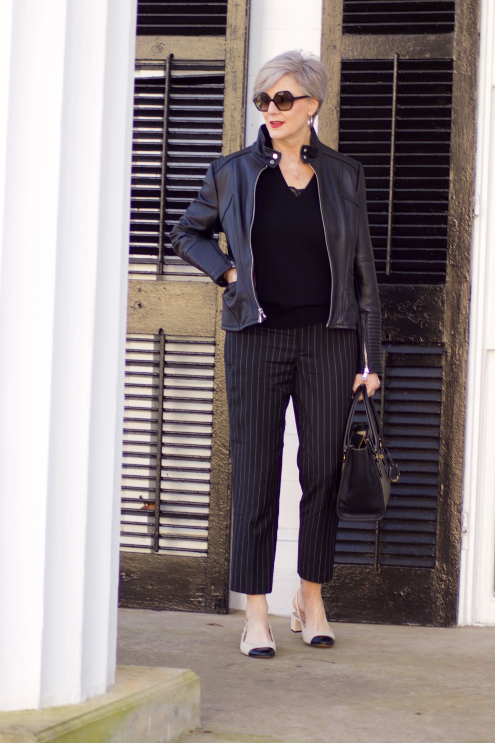 beth from Style at a Certain Age wears Ralph Lauren pinstripe pants, Everlane cashmere sweater, black leather moto jacket, and cap toe slingbacks