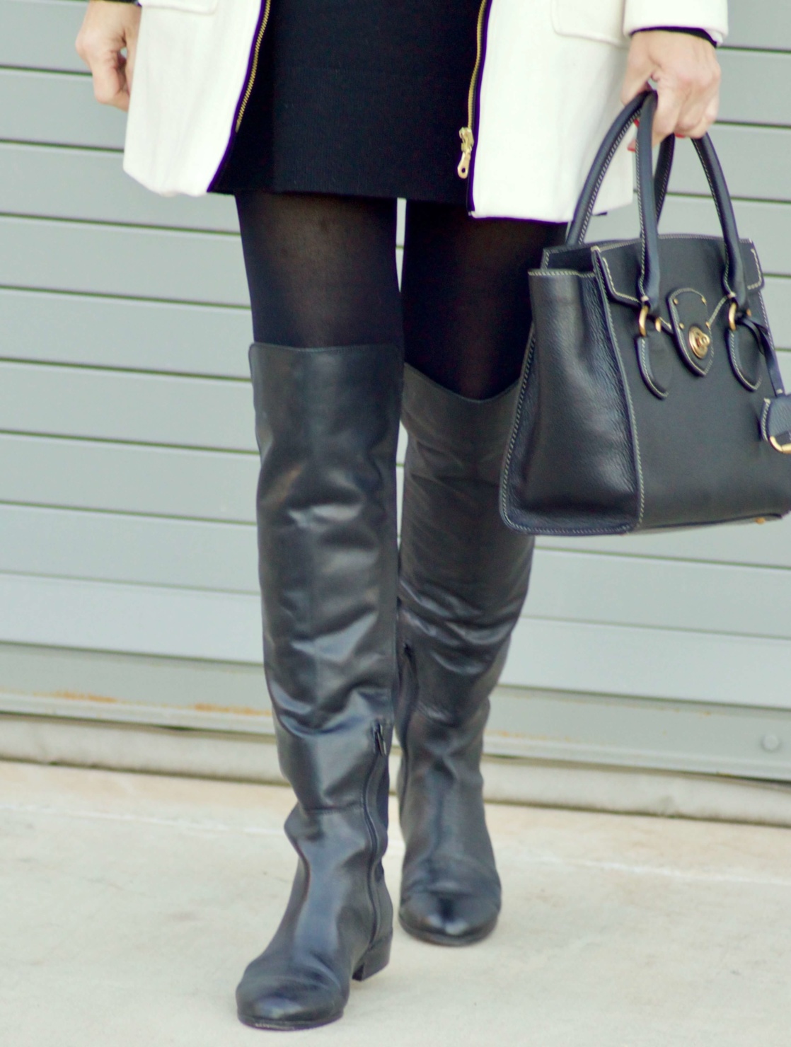 beth from Style at a Certain Age wears a cashmere turtleneck dress, black over the knee boots, and ivory and black coat