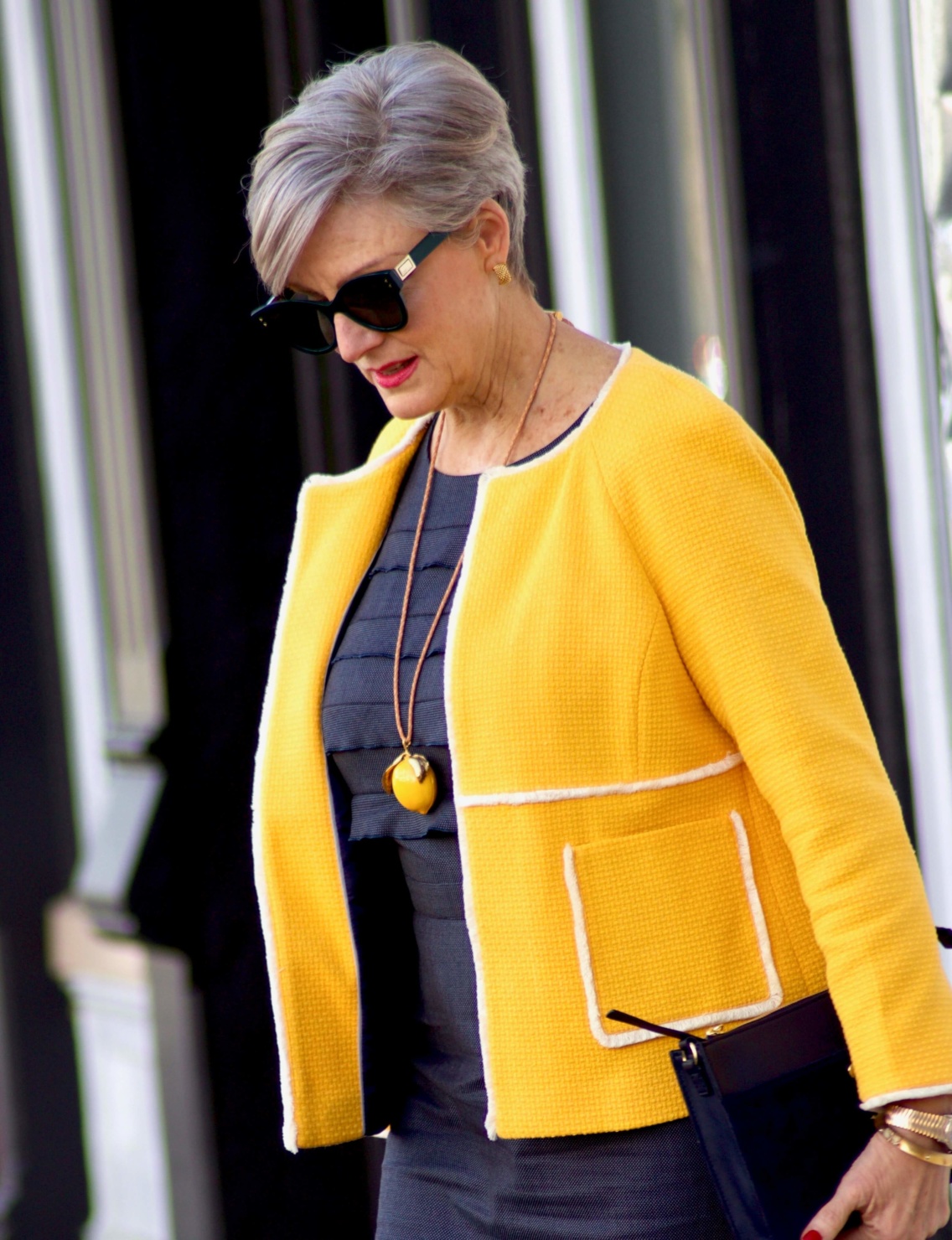 beth from Style at a Certain Age wears a navy blue sheath dress, Boden yellow jacket, navy suede shoes, Tory Burch lemon locket