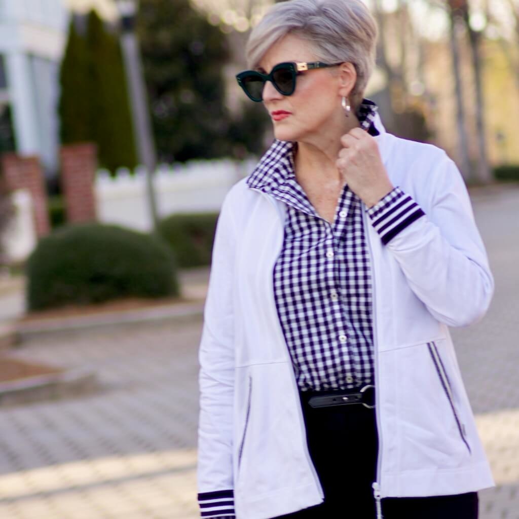 beth from Style at a Certain Age wears a gingham button up, black hampton pants, white track jacket, edison polka dot slingbacks