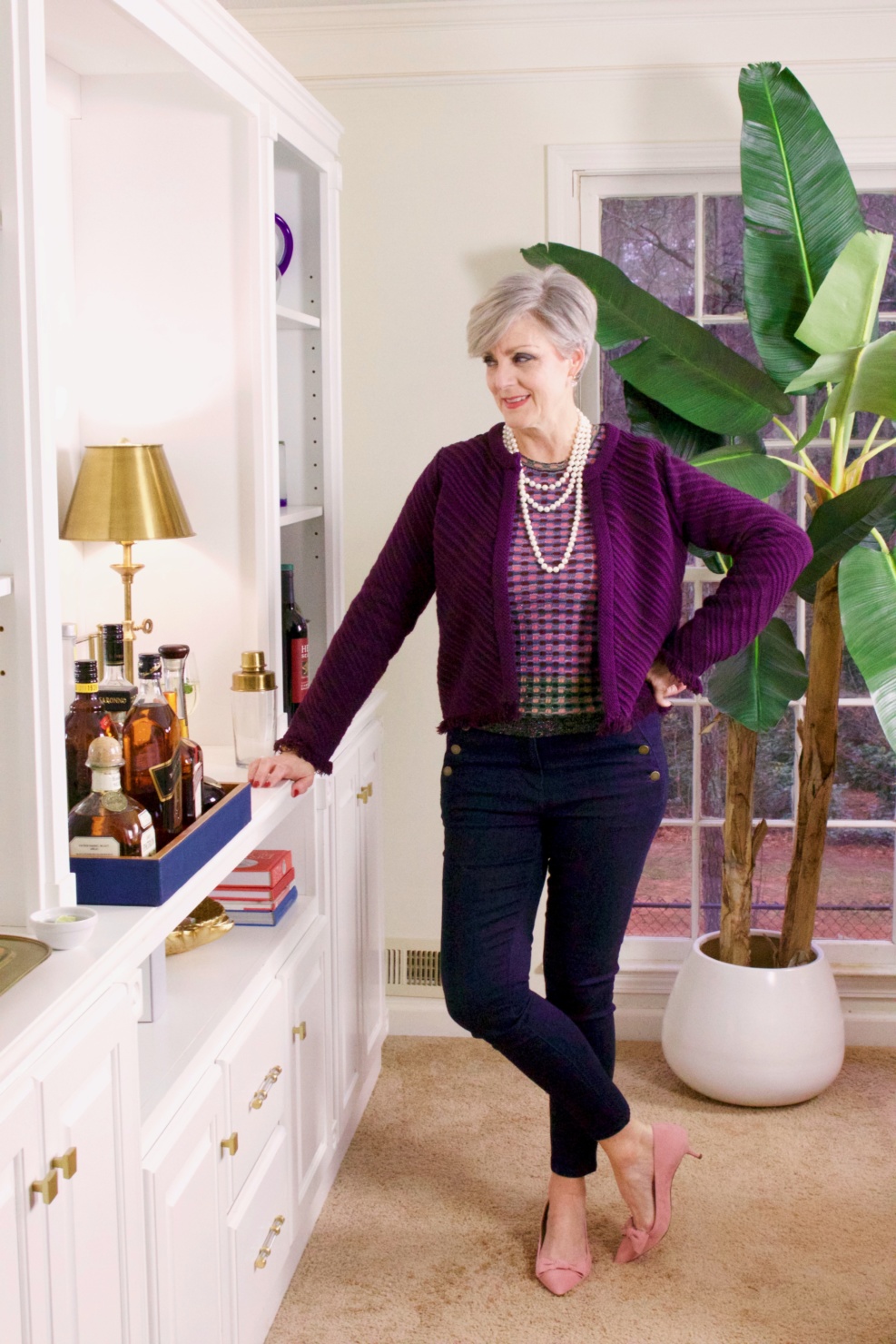 beth from Style at a Certain Age wears a fringed cardigan sweater, denim, and pink suede pumps