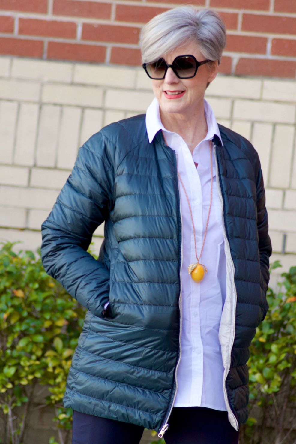 beth from Style at a Certain Age wears Athleta pants, white shirt, puffer jacket, and sneakers