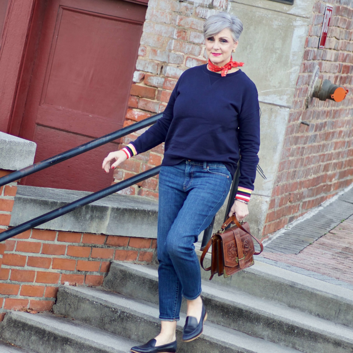 beth from Style at a Certain Age wears a navy blue sweatshirt, blue jeans, Everlane loafers and a J.Crew scarf