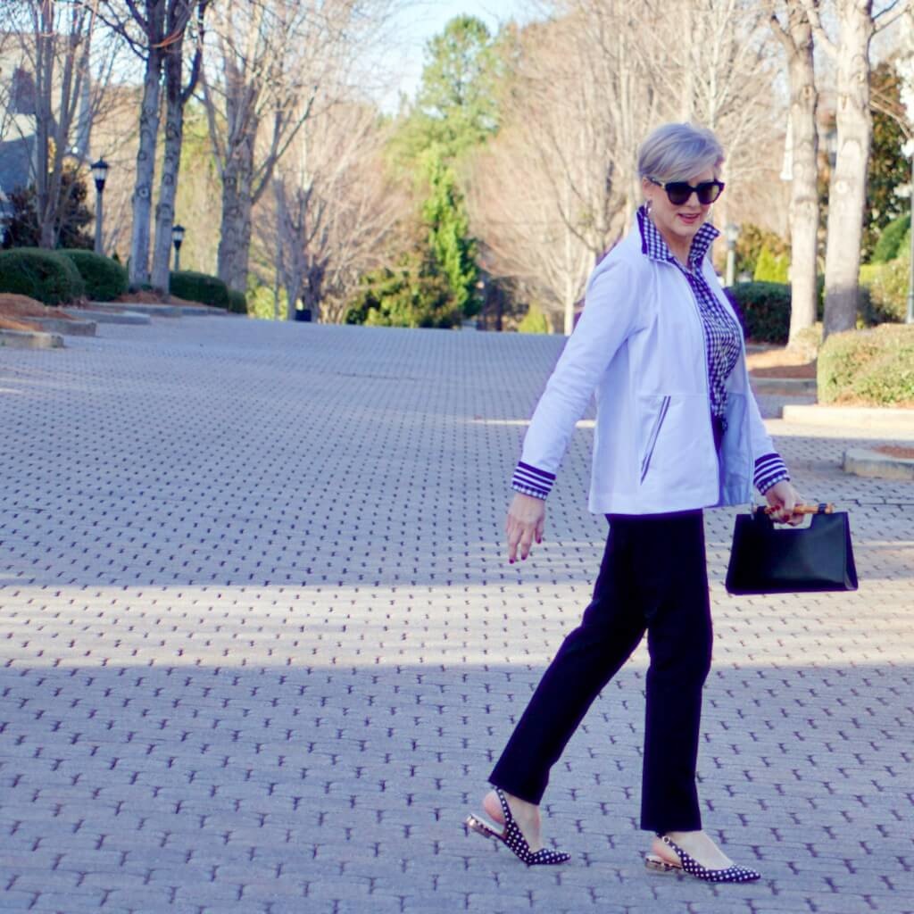 beth from Style at a Certain Age wears a gingham button up, black hampton pants, white track jacket, edison polka dot slingbacks
