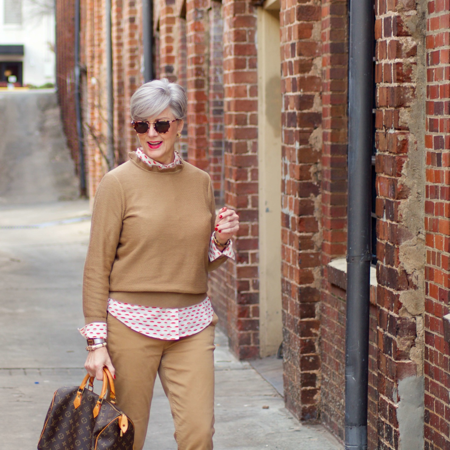 beth from Style at a Certain Age wears a J.Crew camel ruffle neck sweater, slim boy chinos and a Boden modern classic shirt with a bold print.
