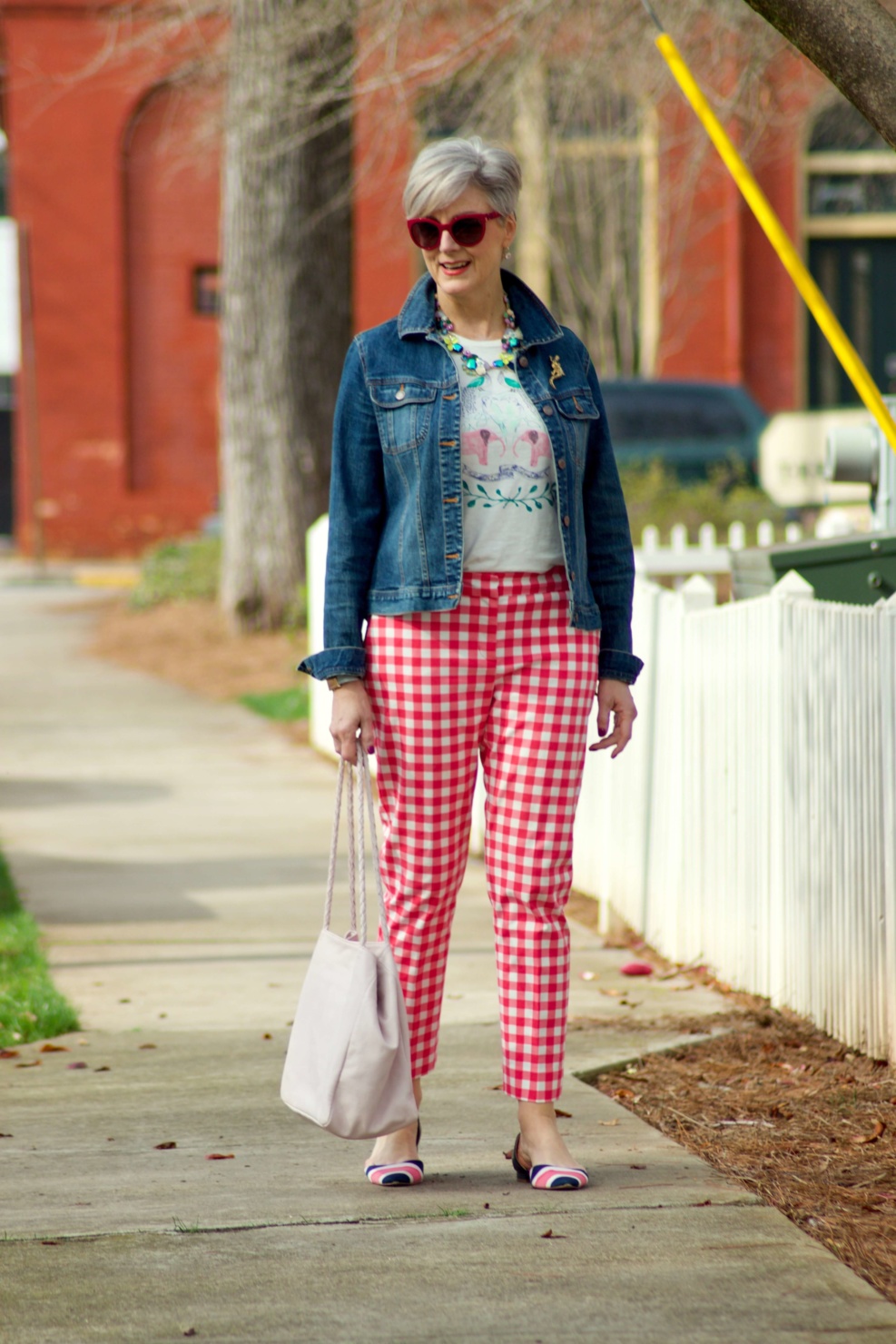 beth from Style at a Certain Age wears pink gingham pants, graphic tee, and denim jacket