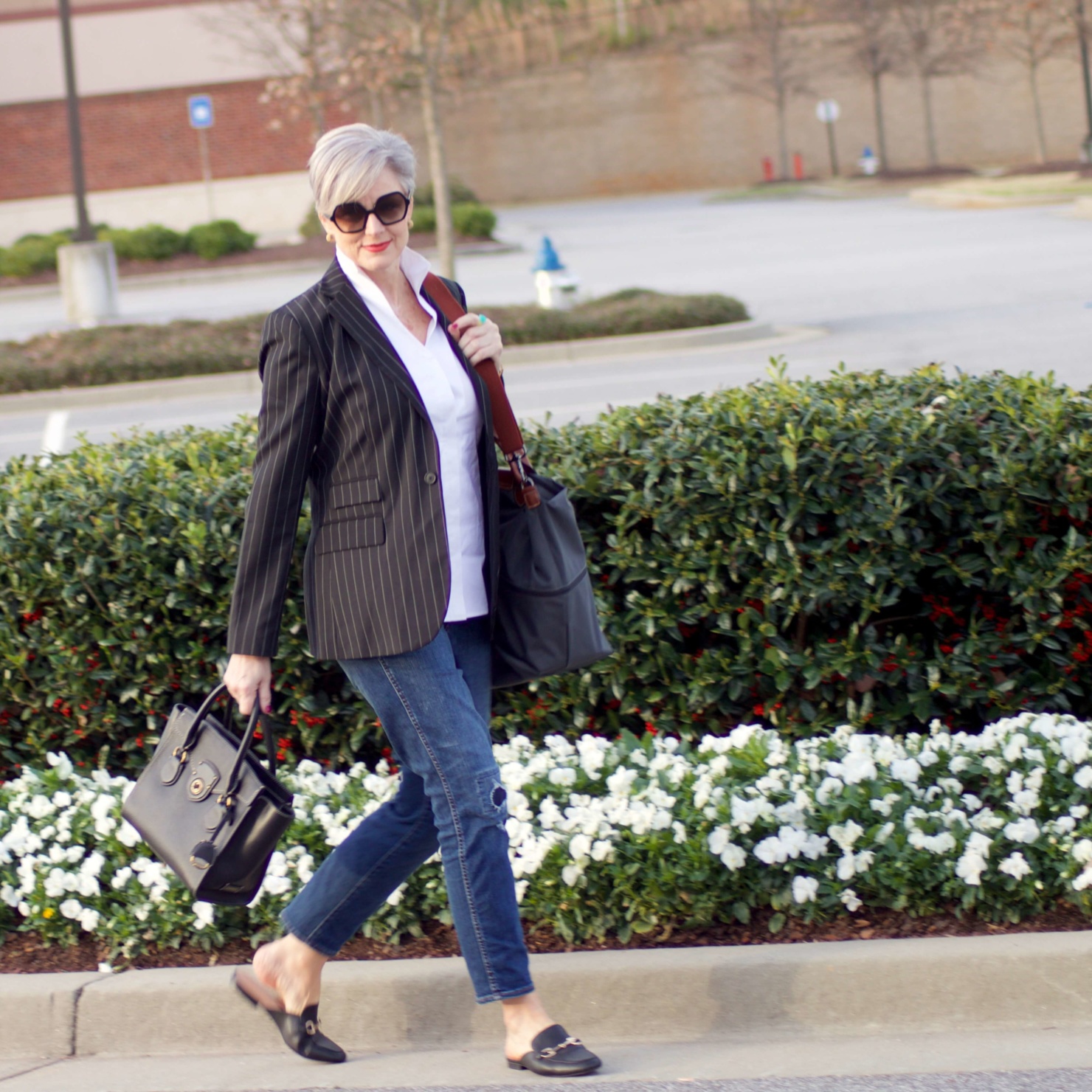 beth from Style at a Certain Age travels in style in a pinstripe blazer, white button down, blue jeans, and black slides
