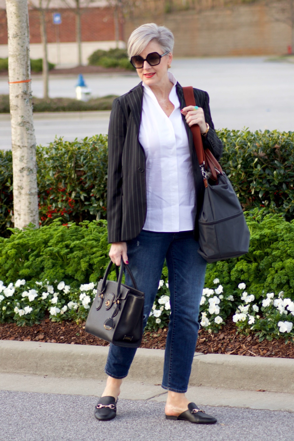 beth from Style at a Certain Age travels in style in a pinstripe blazer, white button down, blue jeans, and black slides