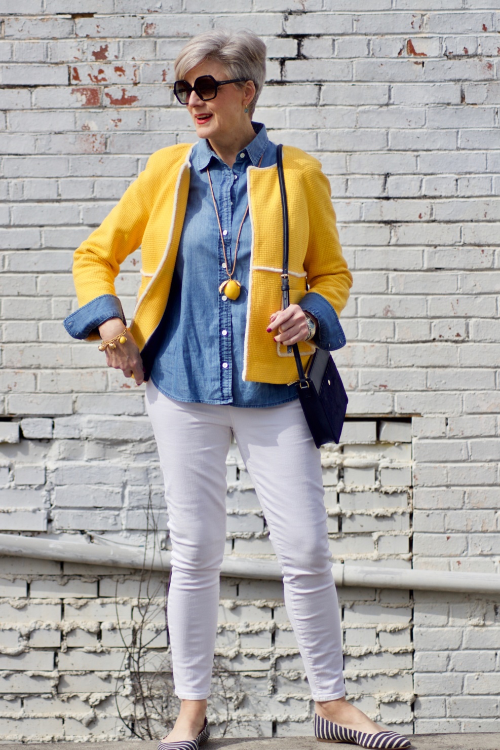 beth from Style at a Certain Age wears a Boden yellow blazer, chambray shirt, white denim and striped shoes