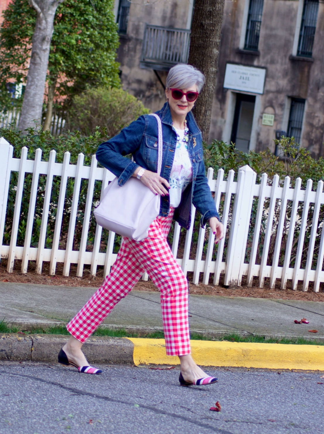 beth from Style at a Certain Age wears pink gingham pants, graphic tee, and denim jacket
