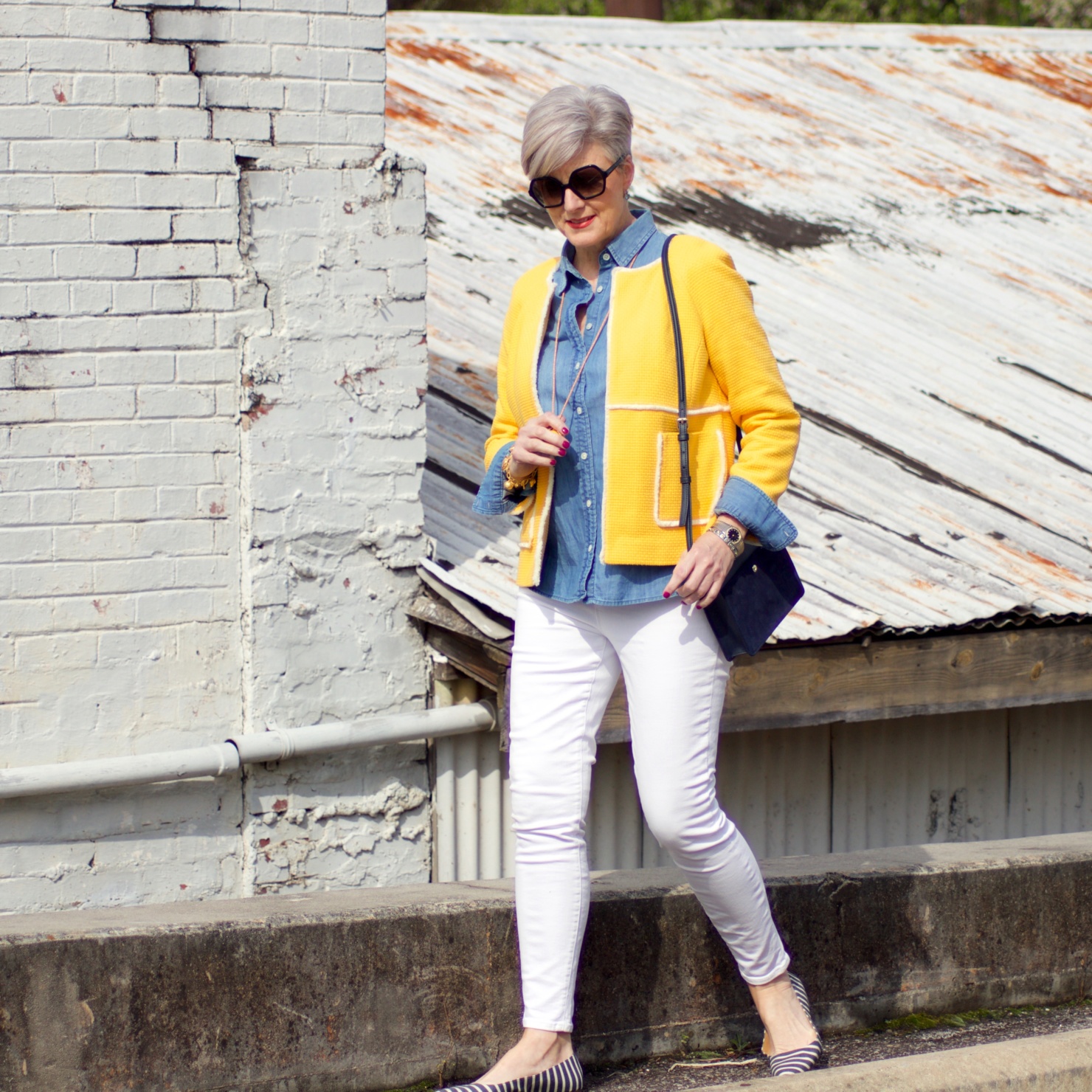 beth from Style at a Certain Age wears a Boden yellow blazer, chambray shirt, white denim and striped shoes