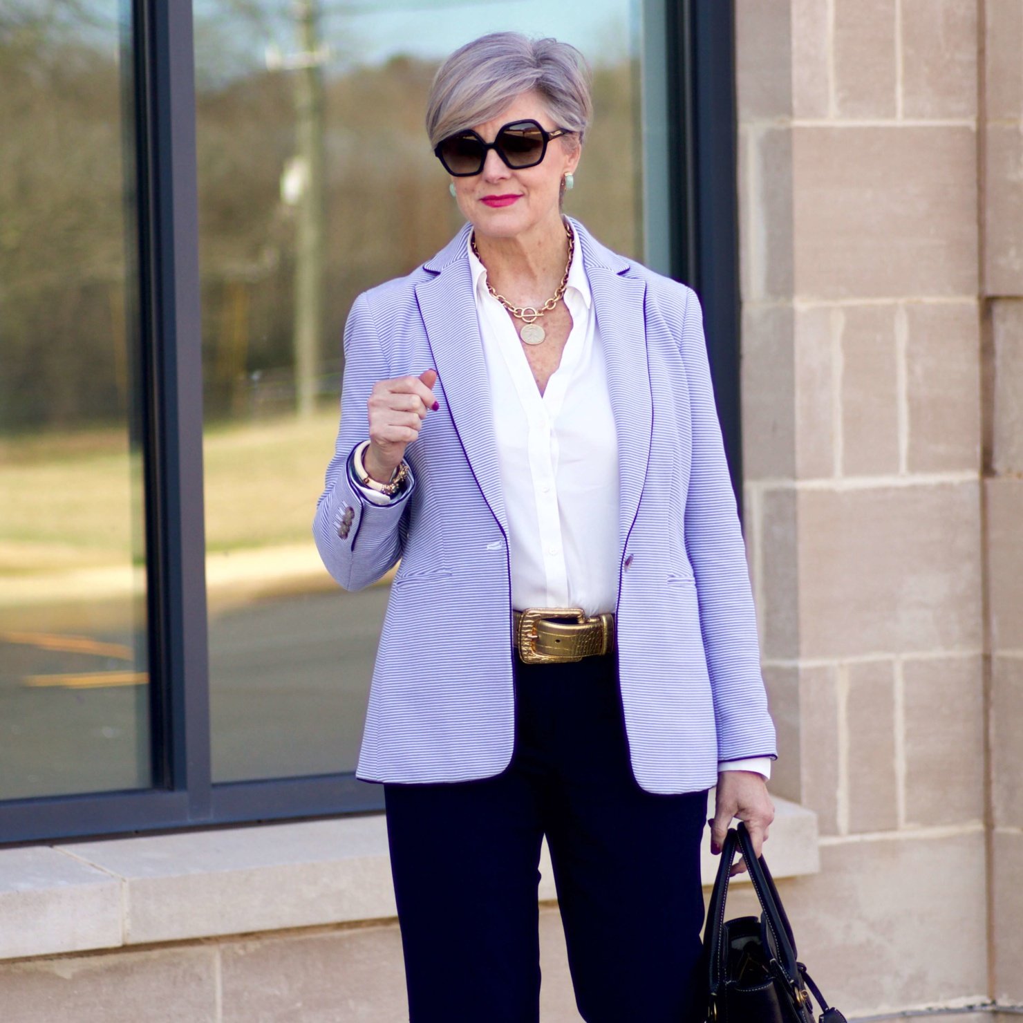 beth from Style at a Certain Age wears a Ann Taylor green trench coat, navy trousers, white essential shirt, knit striped blazer, and green suede pumps.