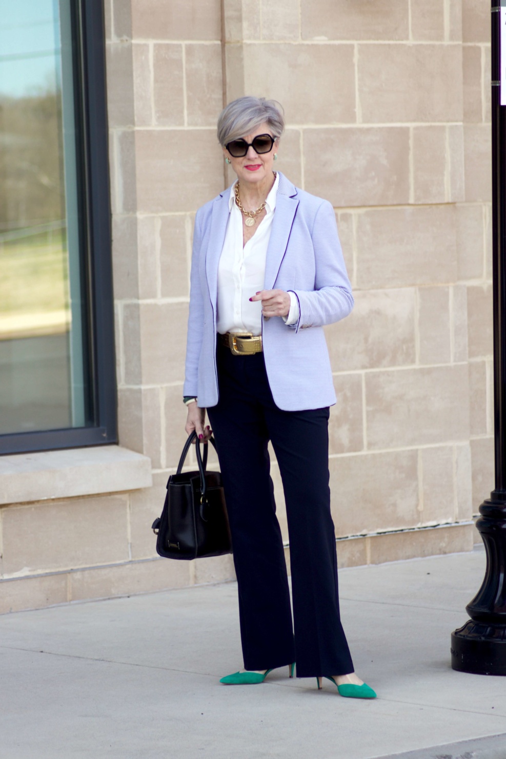 beth from Style at a Certain Age wears a Ann Taylor green trench coat, navy trousers, white essential shirt, knit striped blazer, and green suede pumps.