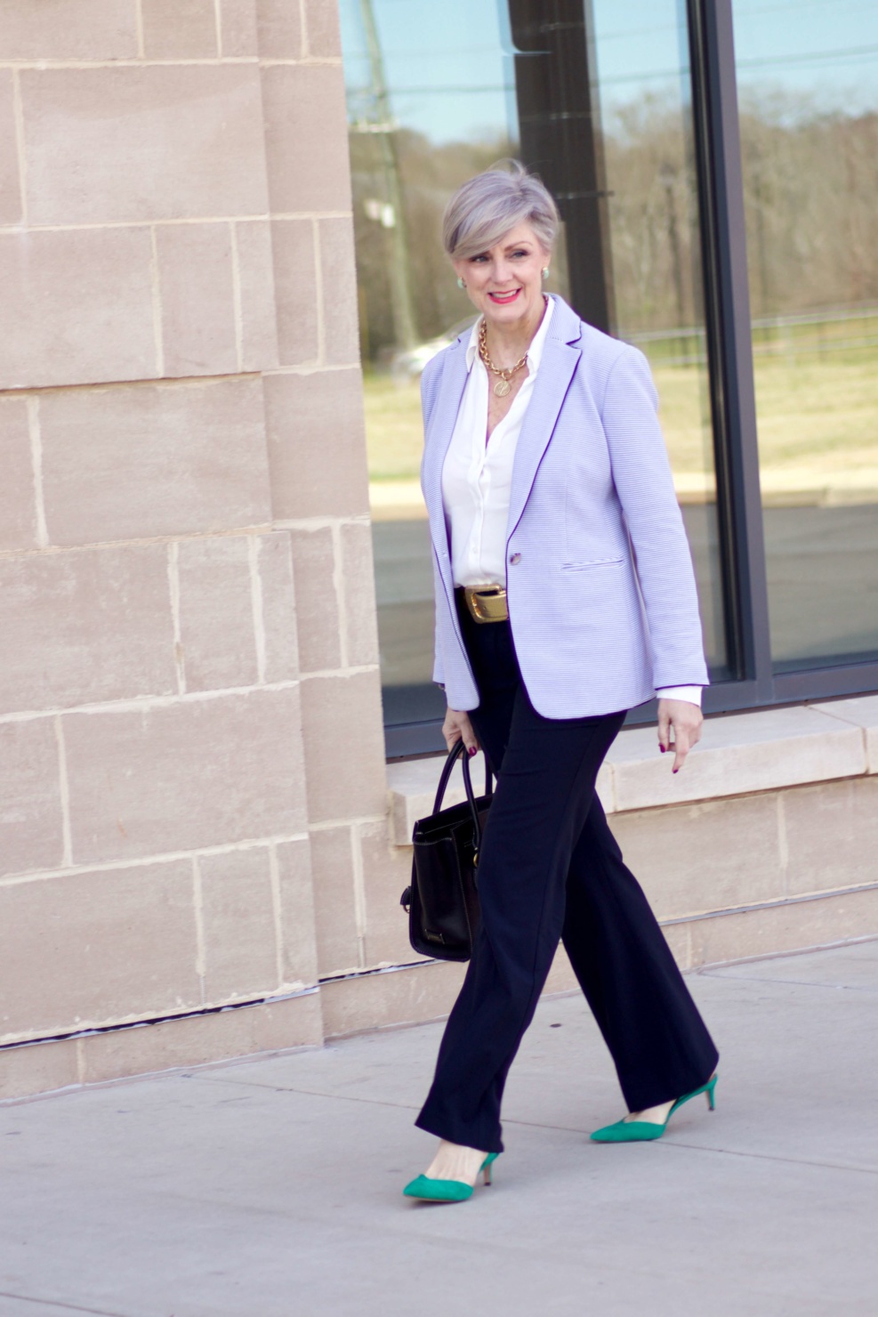 beth from Style at a Certain Age wears a Ann Taylor green trench coat, navy trousers, white essential shirt, knit striped blazer, and green suede pumps.