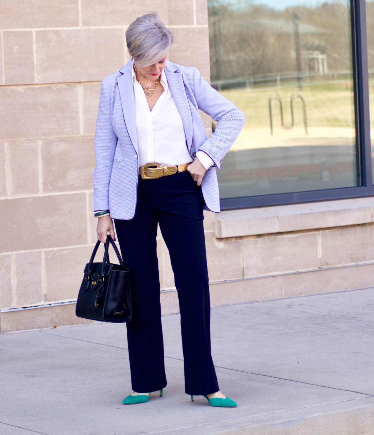 beth from Style at a Certain Age wears a Ann Taylor green trench coat, navy trousers, white essential shirt, knit striped blazer, and green suede pumps.