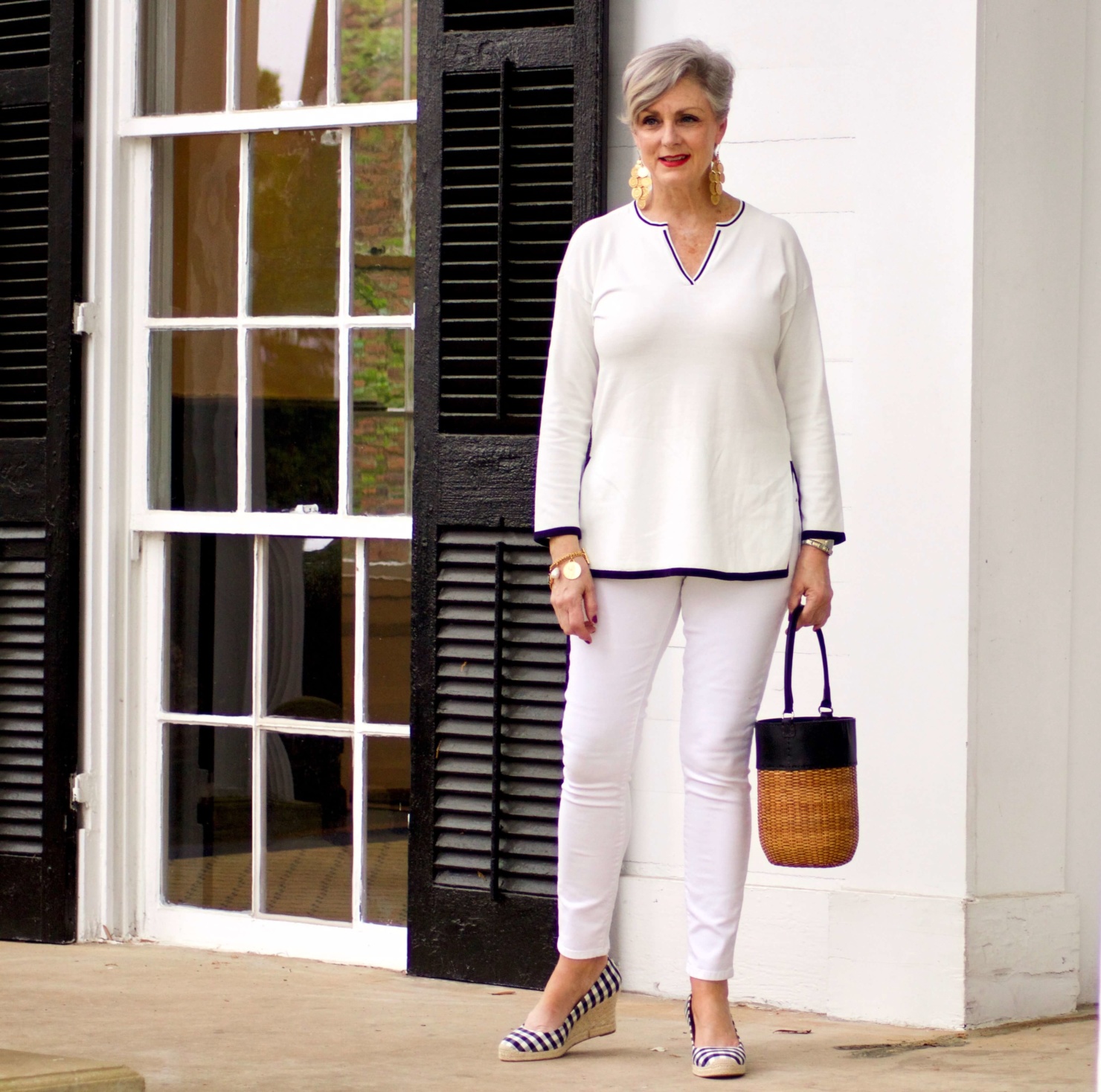 beth from Style at a Certain Age wears a monochromatic white outfit. white tunic trimmed in blue, white jeans and gingham espadrilles