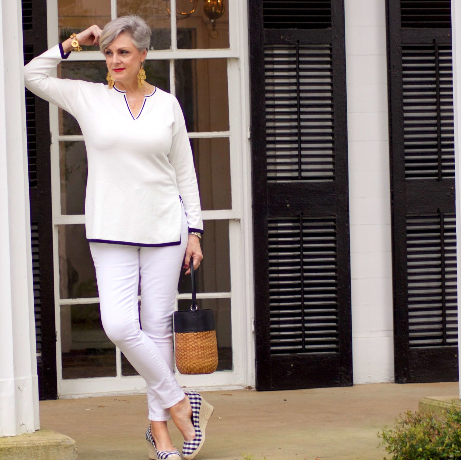 beth from Style at a Certain Age wears a monochromatic white outfit. white tunic trimmed in blue, white jeans and gingham espadrilles