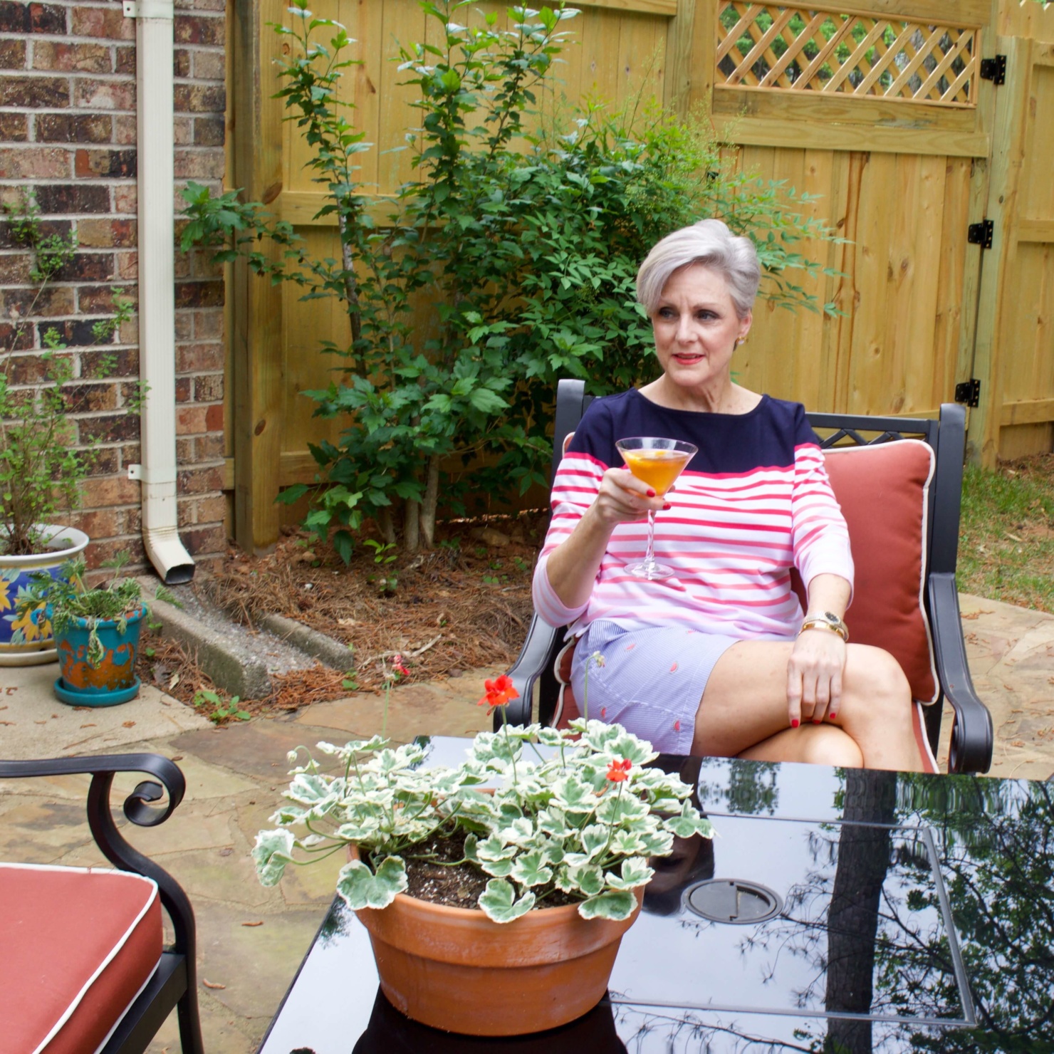 beth from Style at a Certain Age wears watermelon print shorts, striped tee, white jacket and jack rodgers sandals
