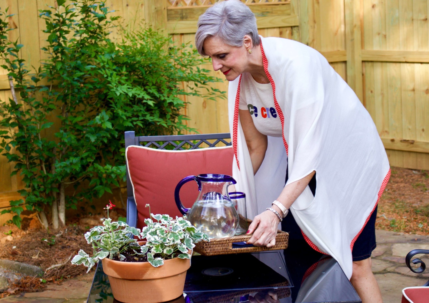 beth from Style at a Certain Age wears a J.Crew graphic tee, jean skirt, lightweight cape scarf, and Tory Burch sandals