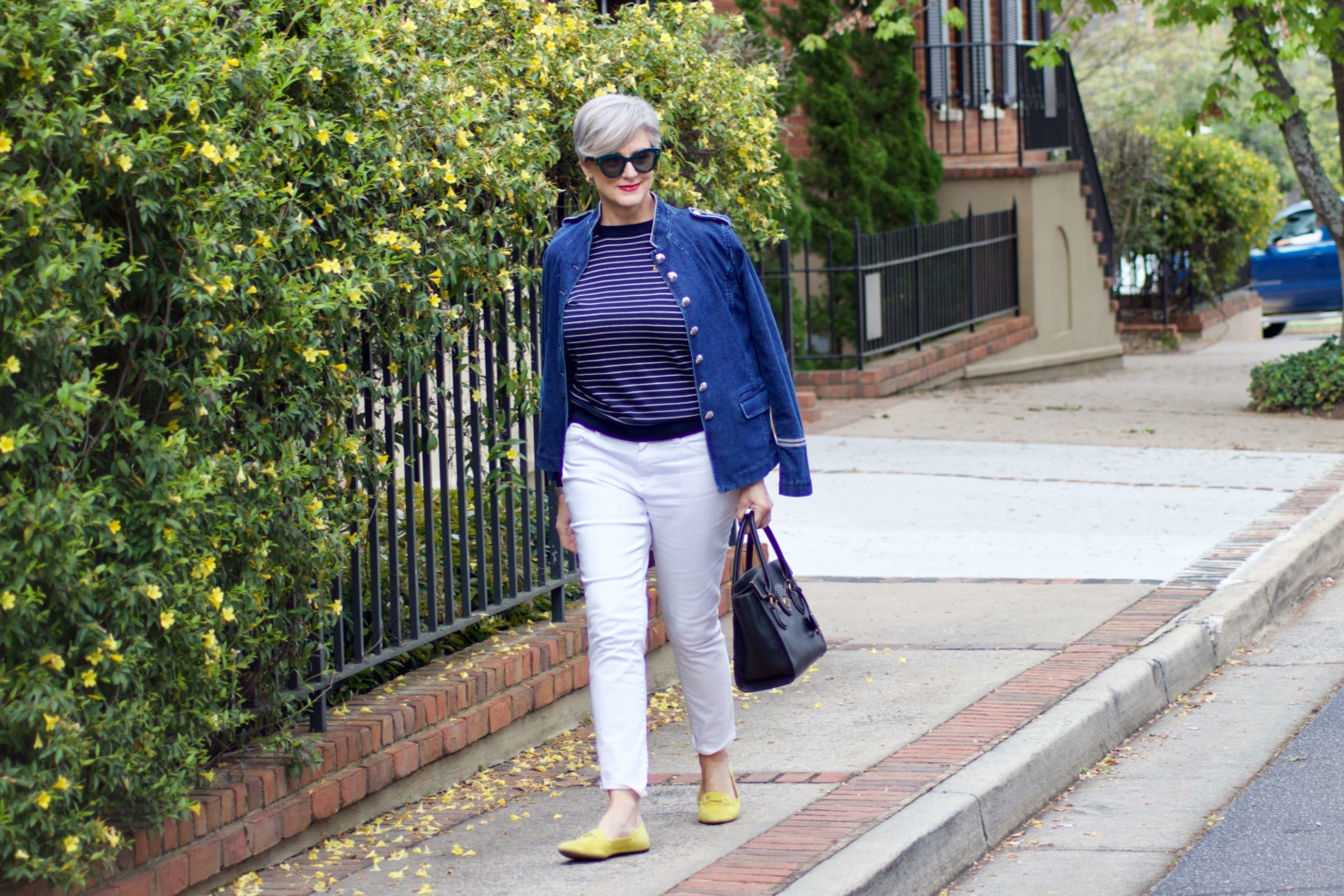 beth from Style at a Certain Age wears a denim military jacket, striped sweater, and white denim
